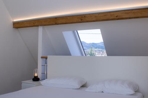 Komfortables Bett direkt unter einem großen Dachfenster, durch das der Himmel sichtbar ist.