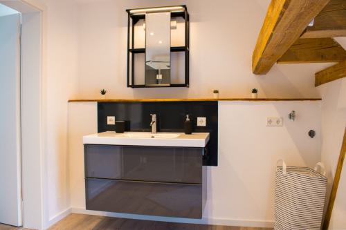 Waschtisch kombiniert rustikale Holzelemente mit modernem Design, ergänzt durch einen kleinen Spiegelschrank in der Ferienwohnung Fronhof