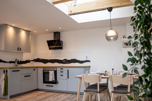 Küchenansicht mit Bergpanorama der Balinger Berge, Esstisch mit Geschirr, Geschirrspüler, Herd, Backofen und Kühlschrank in der Ferienwohnung Fronhof