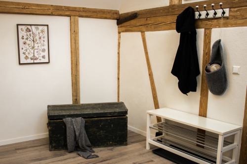 Praktische Garderobe zum Aufhängen von Kleidung neben einer rustikalen, massiven Holztruhe.