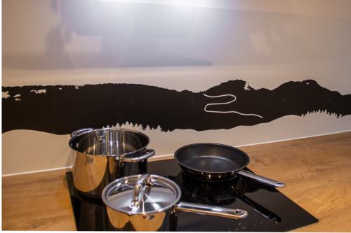 Verschiedene Töpfe und Pfannen auf einem leuchtenden Induktionsherd, bereit zum Kochen.